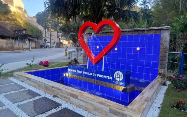 Vista lateral da Fonte Sylvio Trega, com estrutura azul e escultura vermelha em formato de coração.